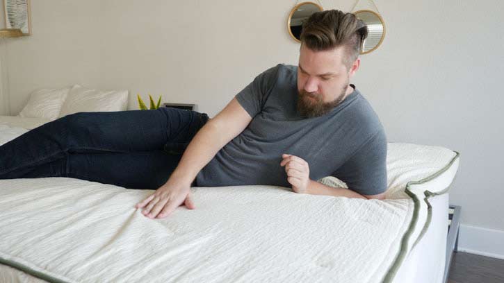 A man feels the top of a mattress topper