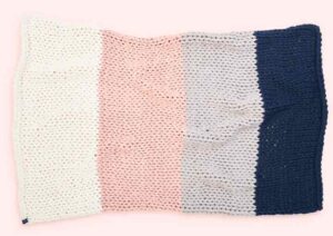 An image of the white, pink, gray, and blue colored bearaby nappling weighted blanket.