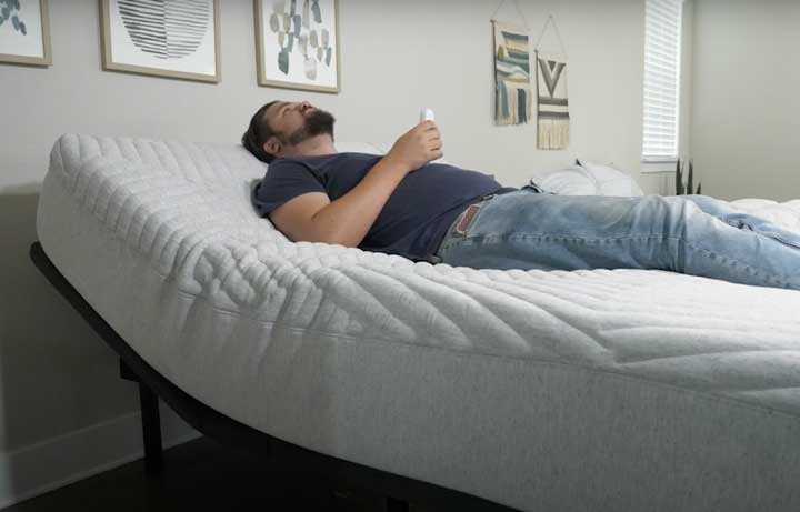 A man lies on the Casper Adjustable base with the head area slightly inclined