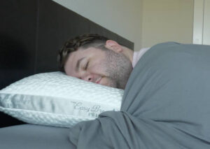 A man sleeps on his stomach with the Nest Easy Breather Pillow