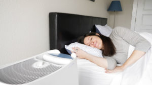 An image of a woman sleeping on her side, facing the Honeywell Germ Free humidifier.