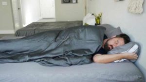 A man sleeps on his side with the LUXOME cooling weighted blanket.