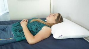 A woman rests on her back with the Purple Harmony pillow