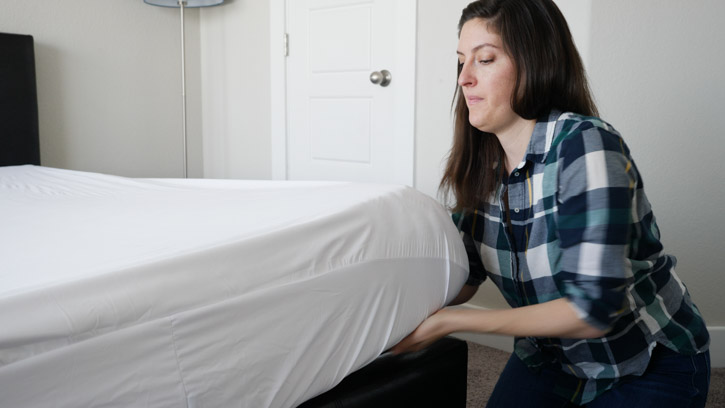 Woman putting protector on mattress