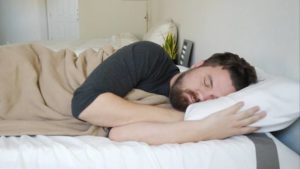 A man sleeps on his side using the SoftHeat Luxury Fleece Heated Blanket.