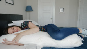 A woman sleeps on her side hugging the TEMPUR-Pedic Body Pillow